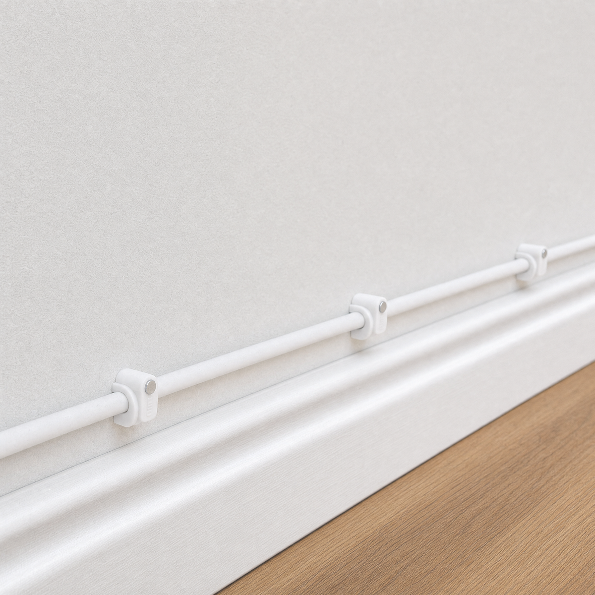 QualGear 6 mm cable clip in white mounted along a light wall and baseboard, nail driven straight in