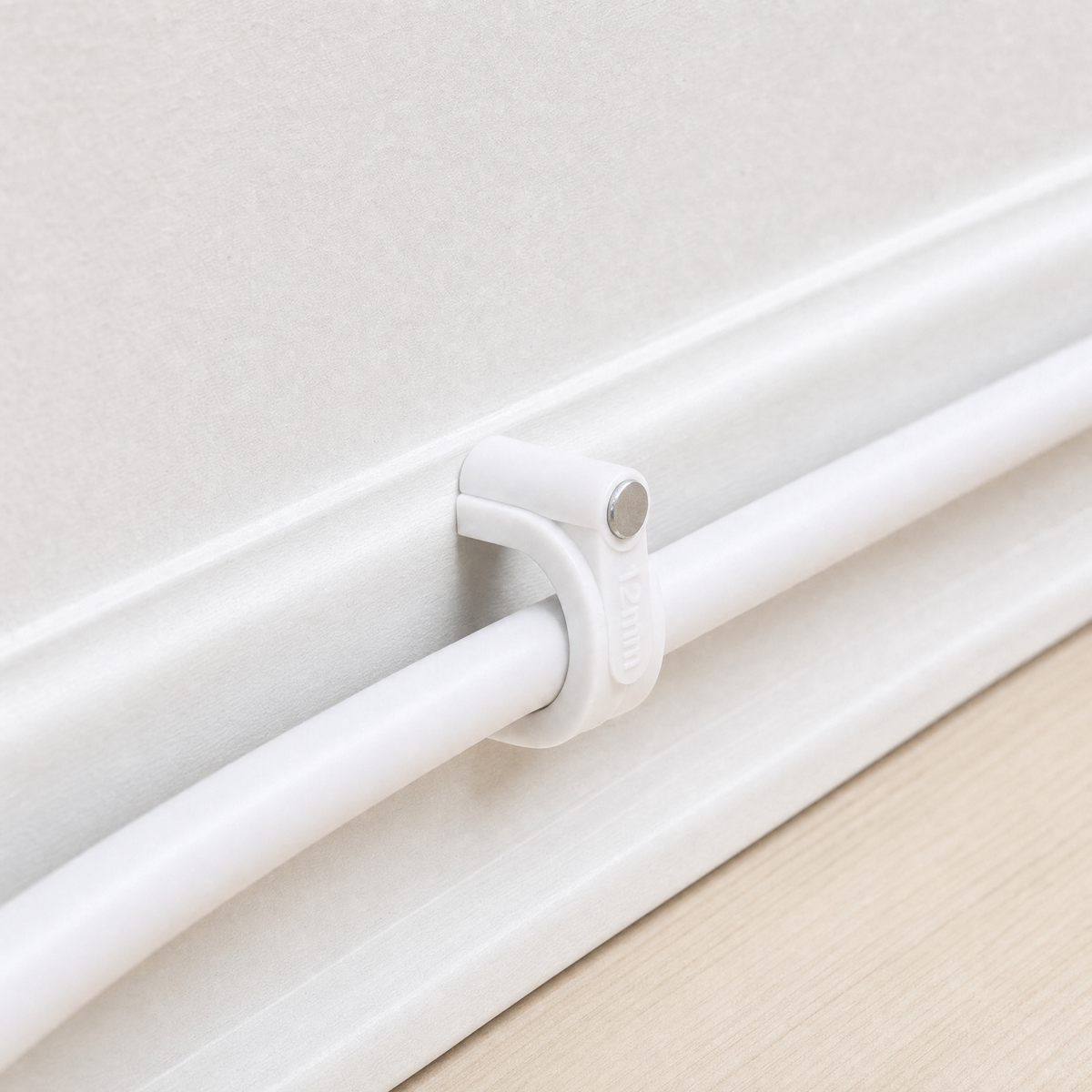 QualGear 12 mm cable clip in white, the largest size, mounted along a light-colored wall