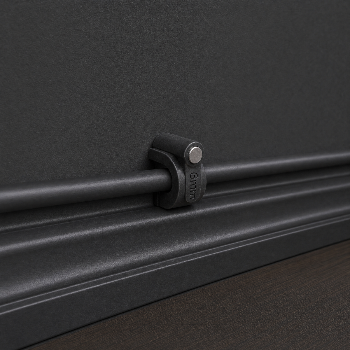 QualGear 6 mm cable clip in black holding a coax cable close against a dark wall surface