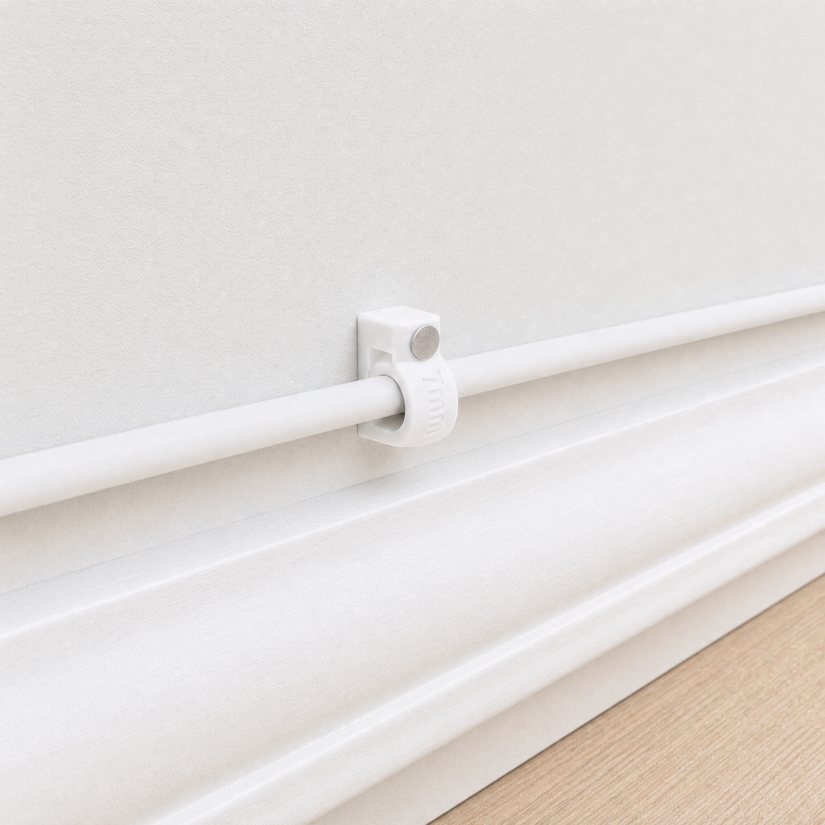 QualGear 7 mm cable clip in white holding a white cable flush along a light wall