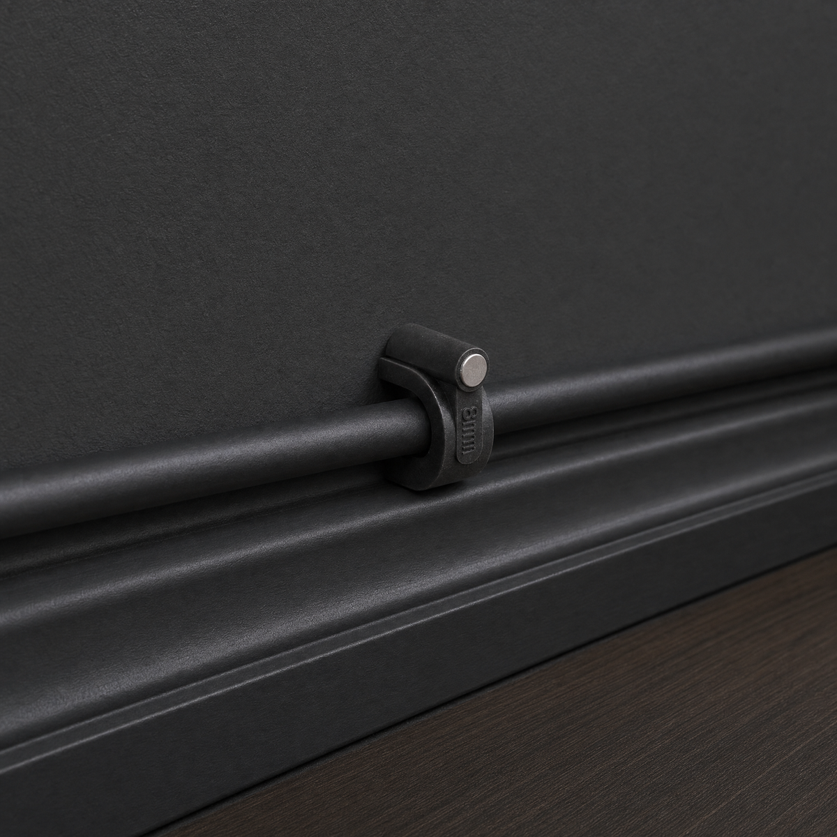 QualGear 8 mm cable clip in black securing a black cable flush along a black wall and baseboard