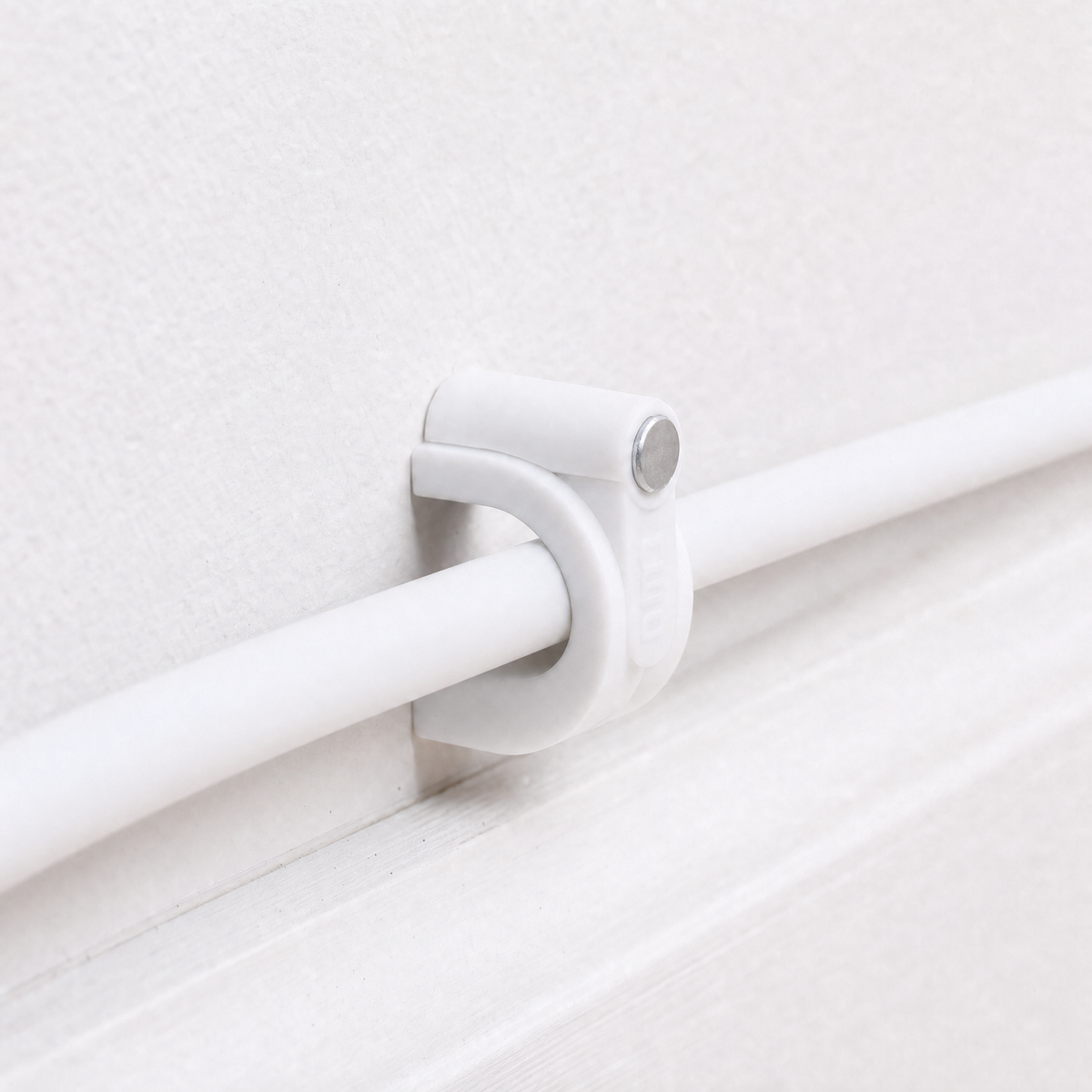 QualGear 8 mm cable clips in white holding a white cable in a straight line along a light wall