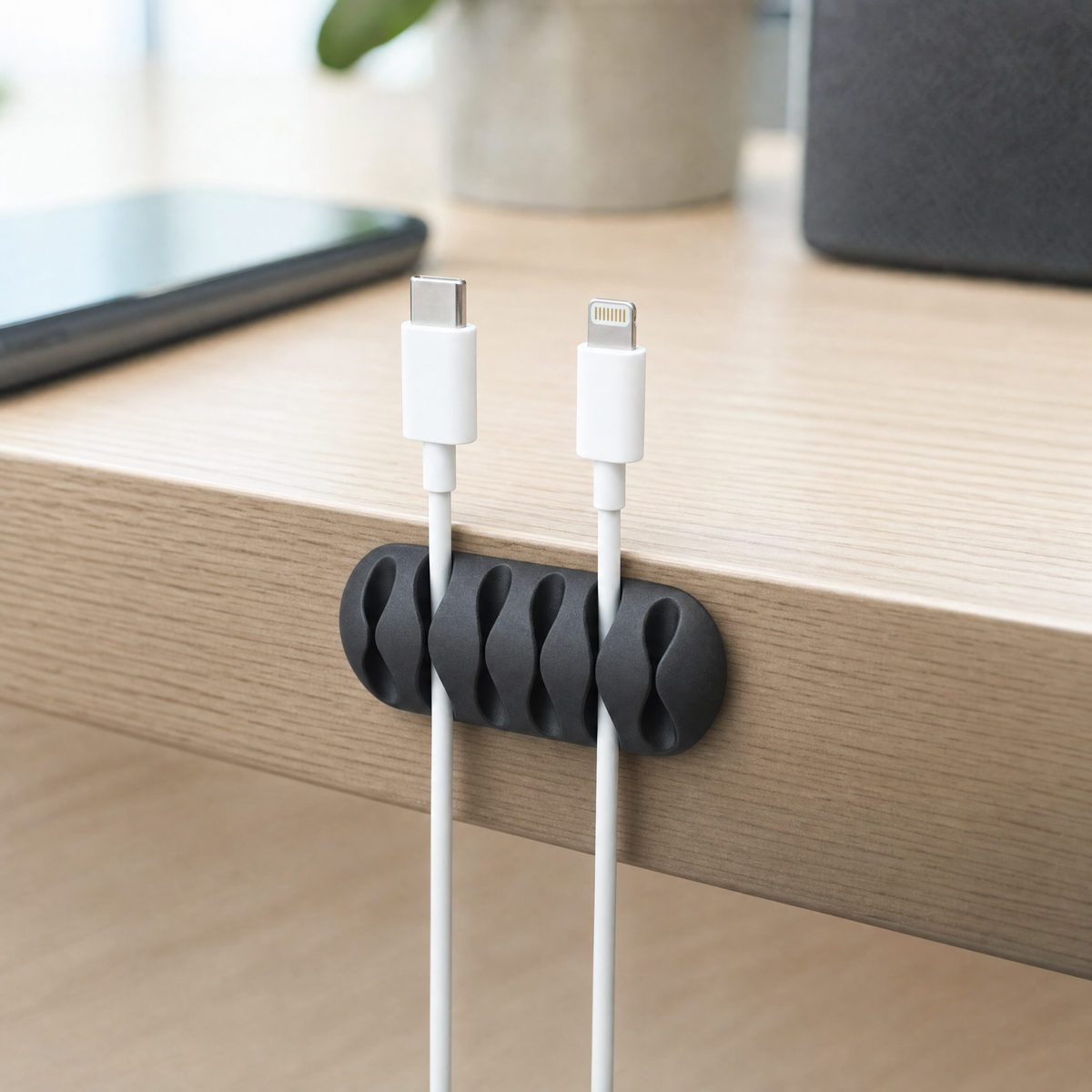 QualGear cable clip holder in black mounted on a desk edge, guiding two cables from a charger