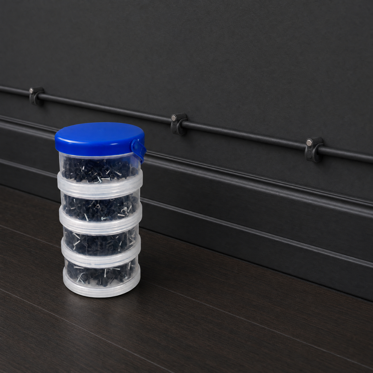 QualGear 400-pack cable clip canister in black (4, 6, 8, 10 mm) beside clips mounted on a black wall
