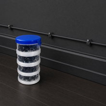 QualGear 400-pack cable clip canister in black (4, 6, 8, 10 mm) beside clips mounted on a black wall